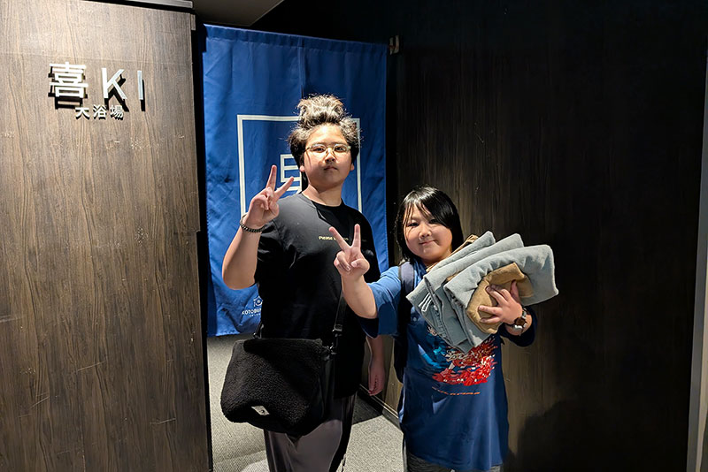 男湯のノレンの前でピースサインをする兄弟