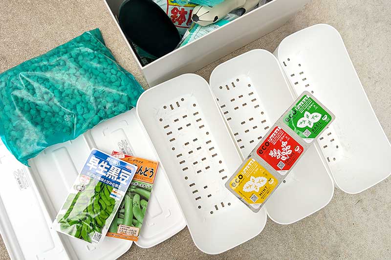 複数の白い植木鉢とネット・底石・スナップエンドウと黒豆・ハーブの種